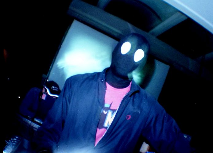 a man in a mask standing with a cell phone