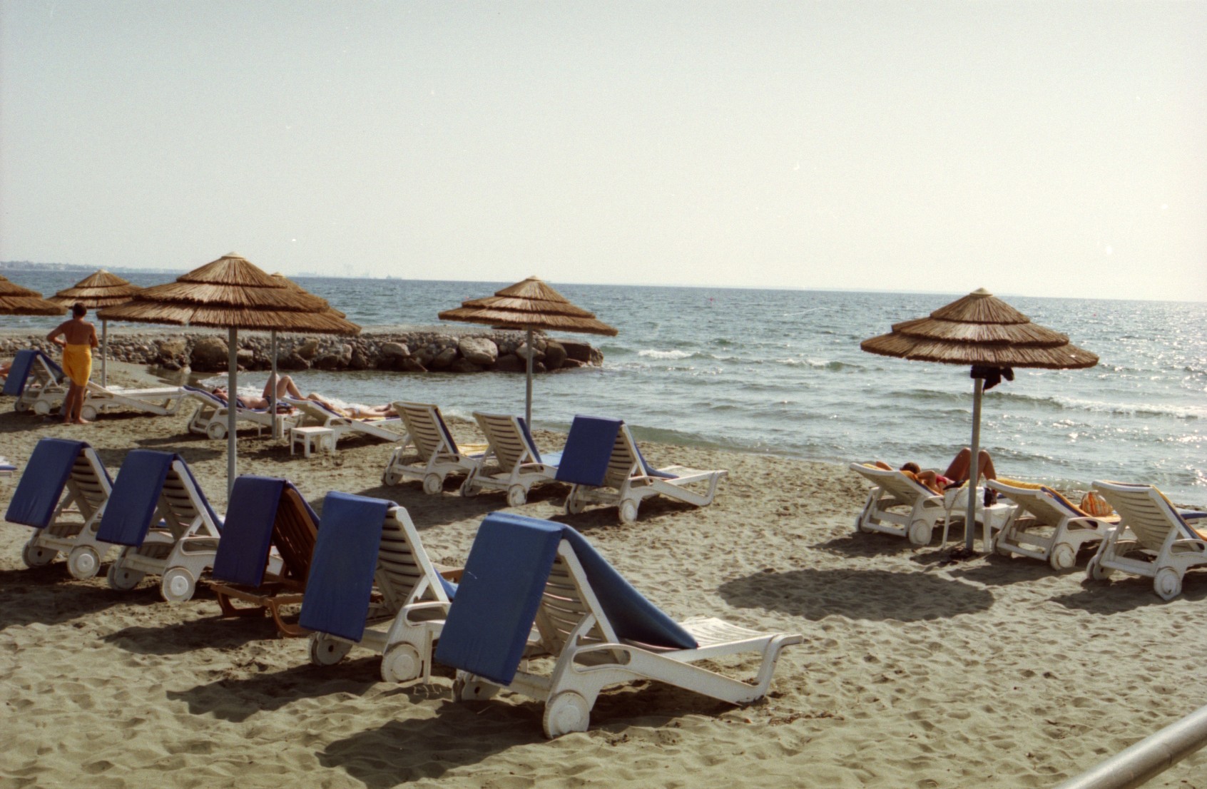 a beach with chaise lounges and umbrellas on the sand