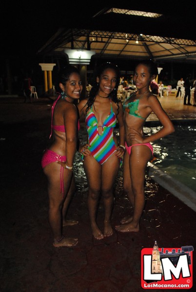 three women in bathing suits posing in front of the pool