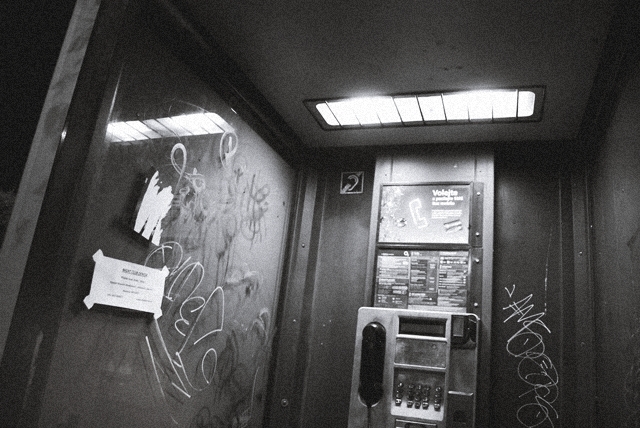 a locker with graffiti on it next to a telephone