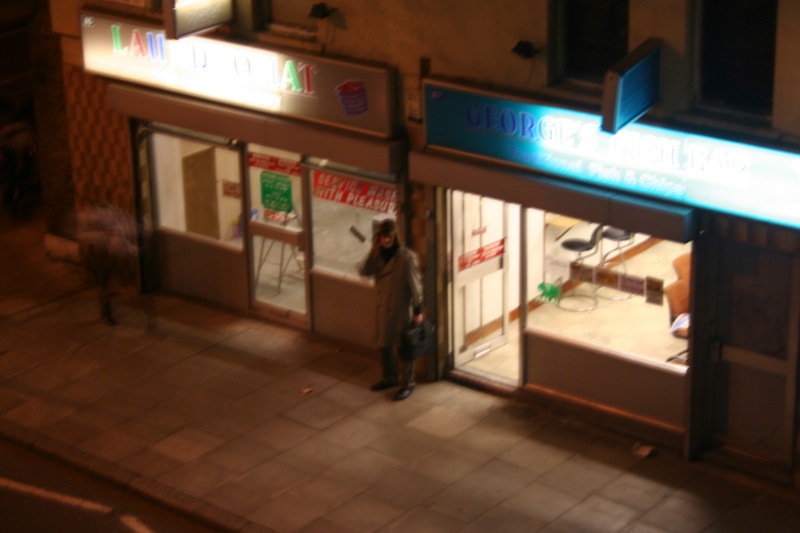 a man standing on a sidewalk in front of a shop