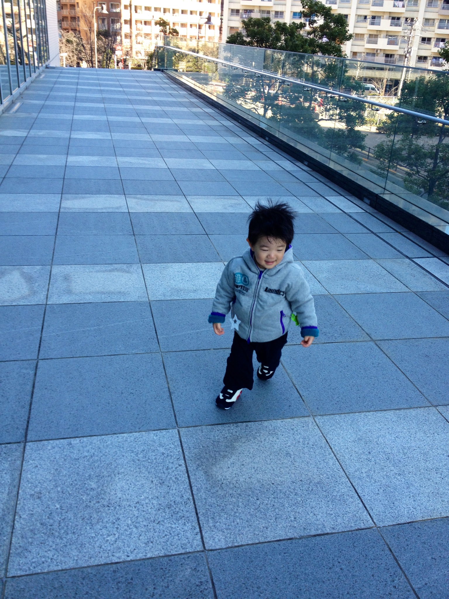 a little boy walking across a walkway next to buildings