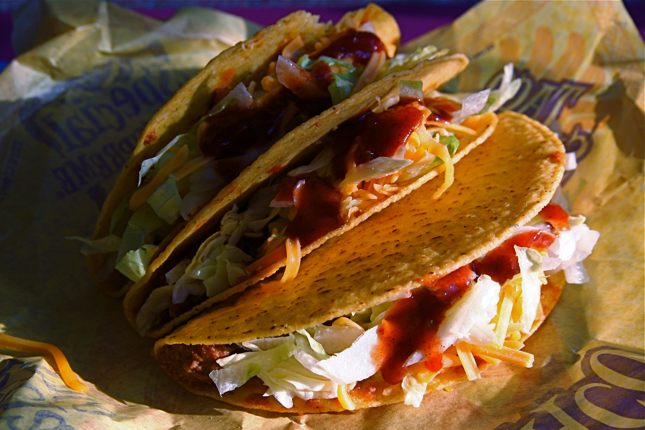 a taco sandwich on a wrapper covered in toppings