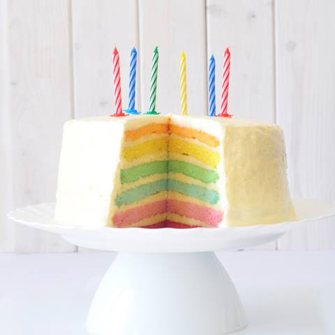 a triple layer cake with lit candles sitting on top of a white plate