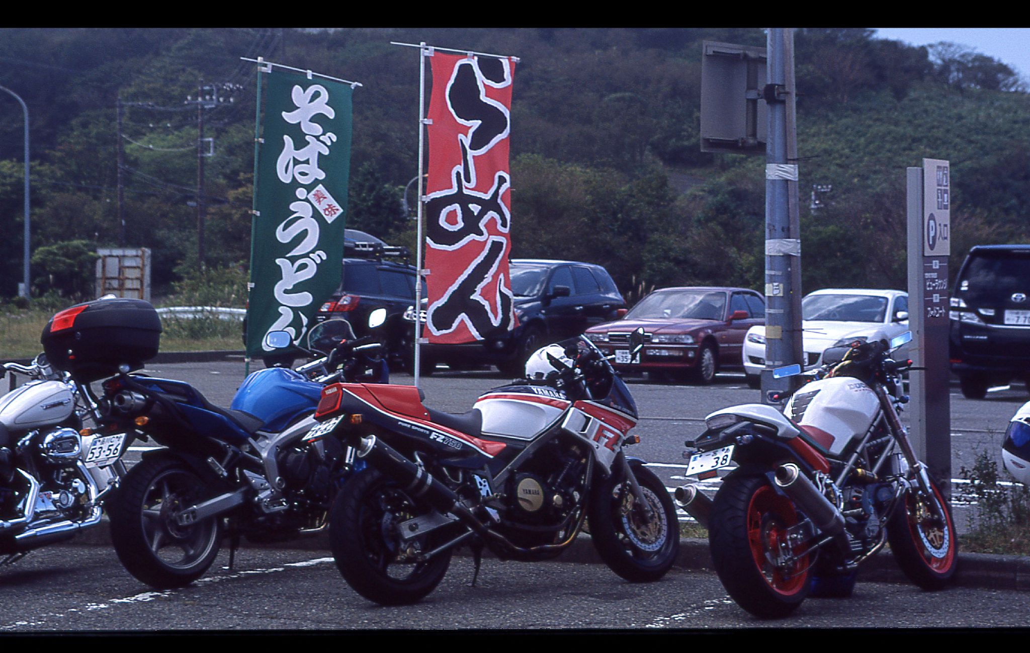 three motorbikes in an asian language are parked on the side of a road