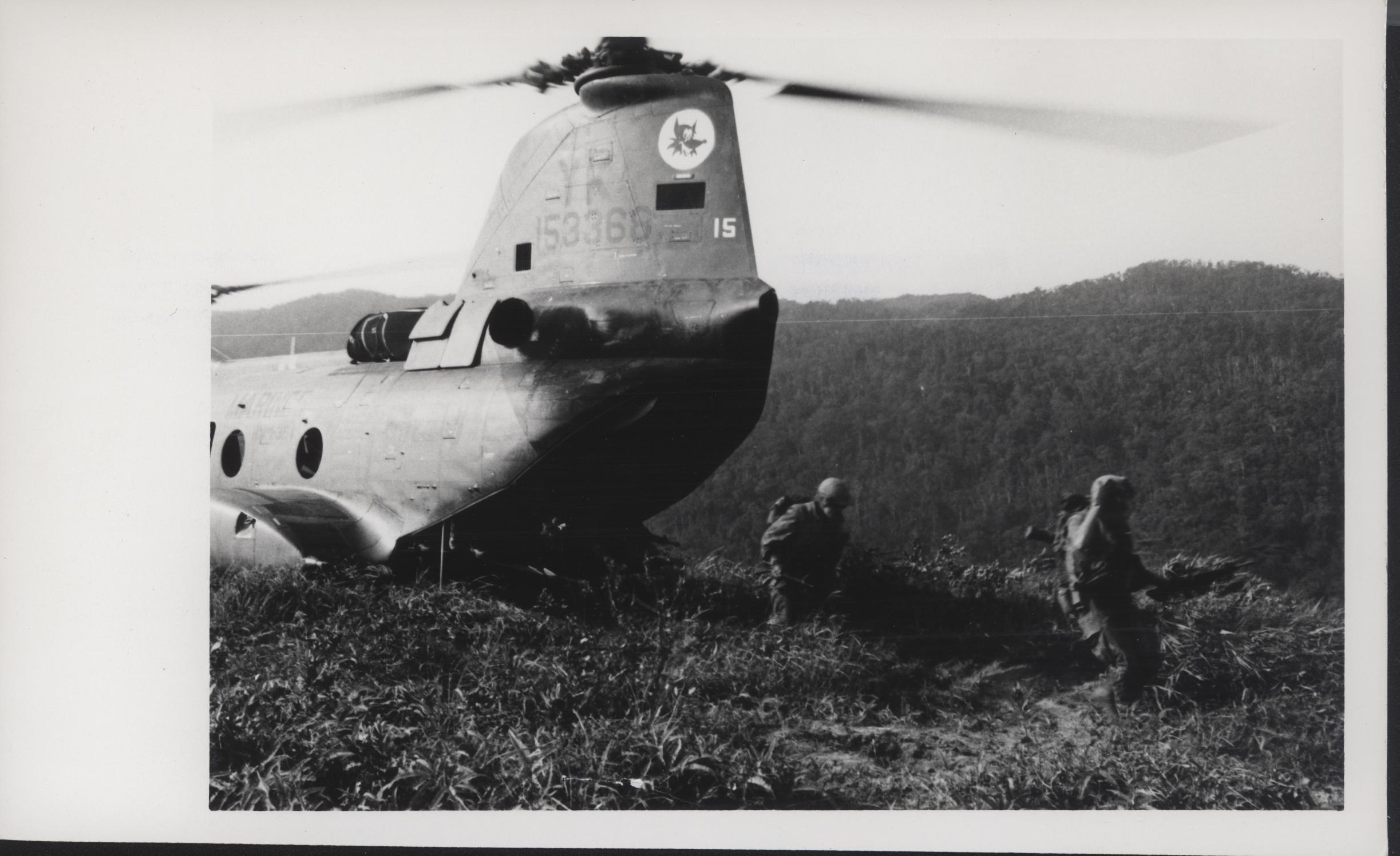an old po of two soldiers in front of a helicopter