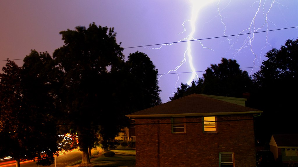 a very bright, purple lightning over a residential neighborhood