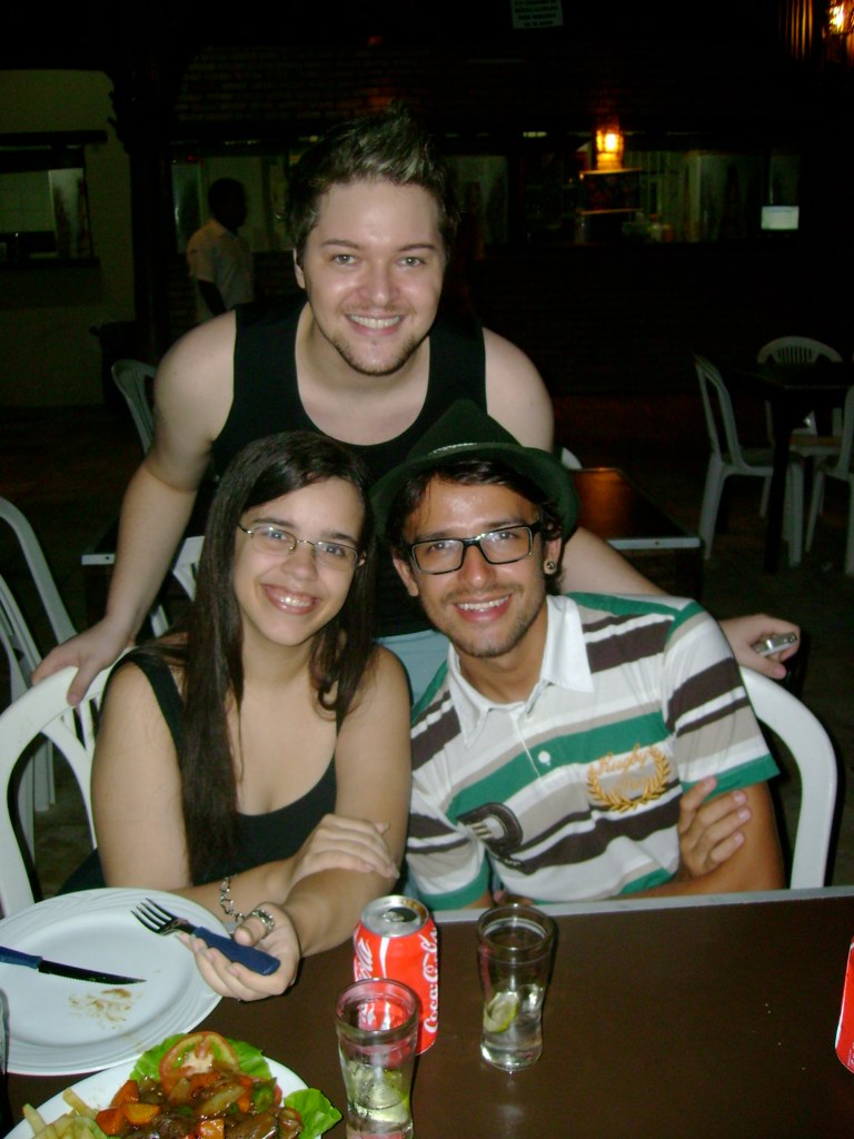 a couple poses for a picture while enjoying dinner in front of some friends