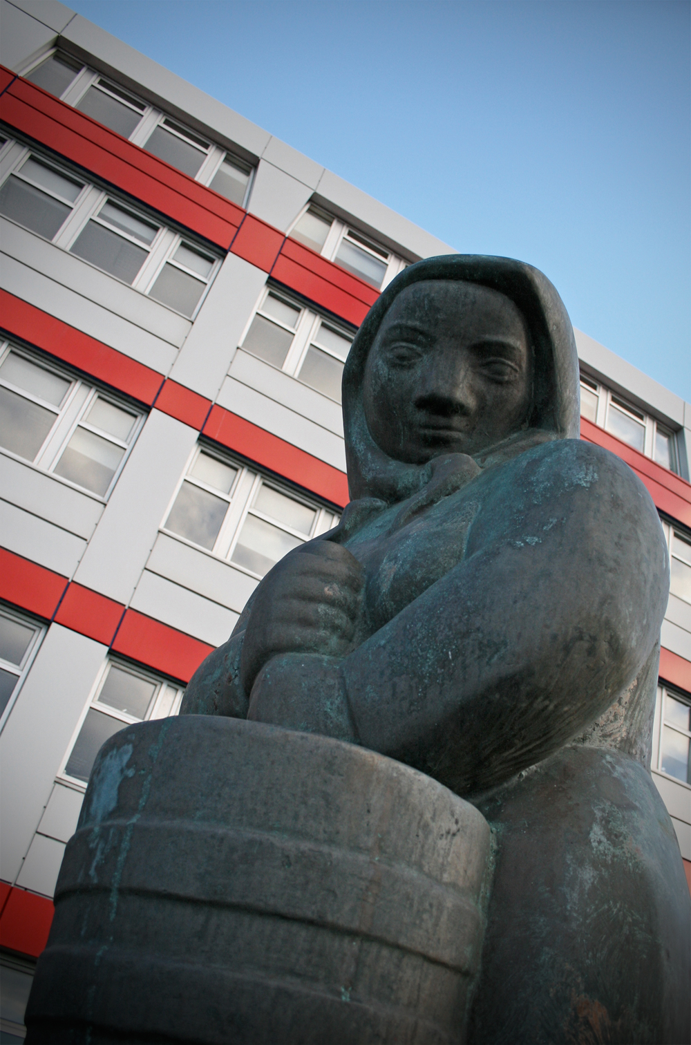 a statue that looks like a woman is sitting in front of a building