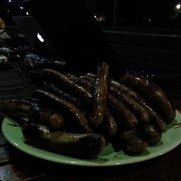 a green plate topped with sausages on top of a wooden table