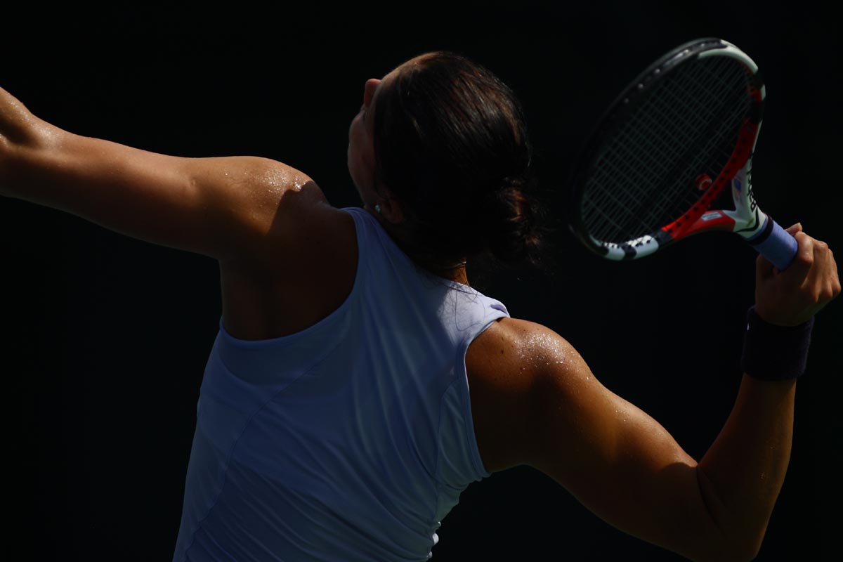 a woman holding a tennis racquet at the end of a serve