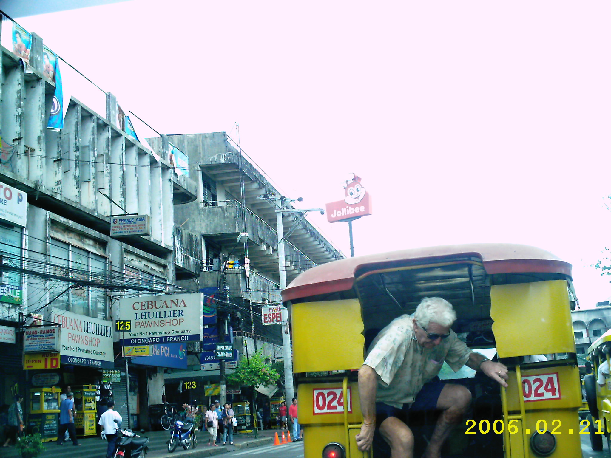 a man sitting on the back of a bus driving down a street