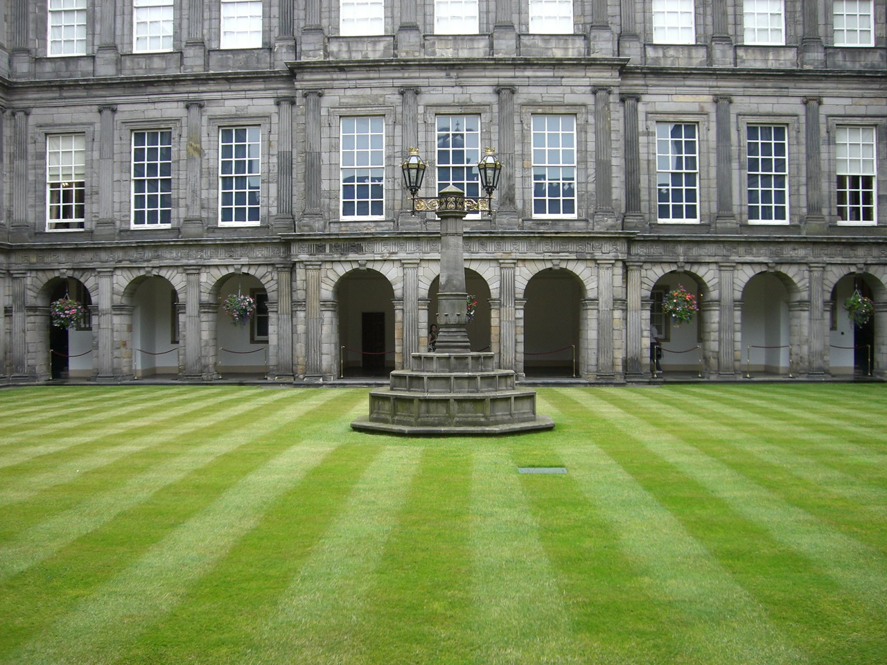 the outside of a large building with a fountain in a front lawn
