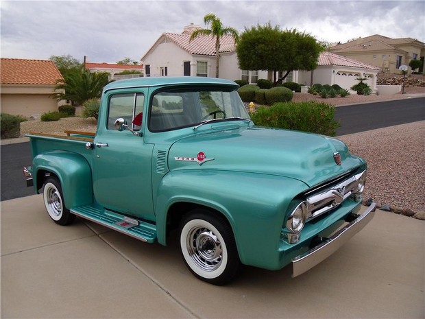 the vintage green truck is parked on the side of the road