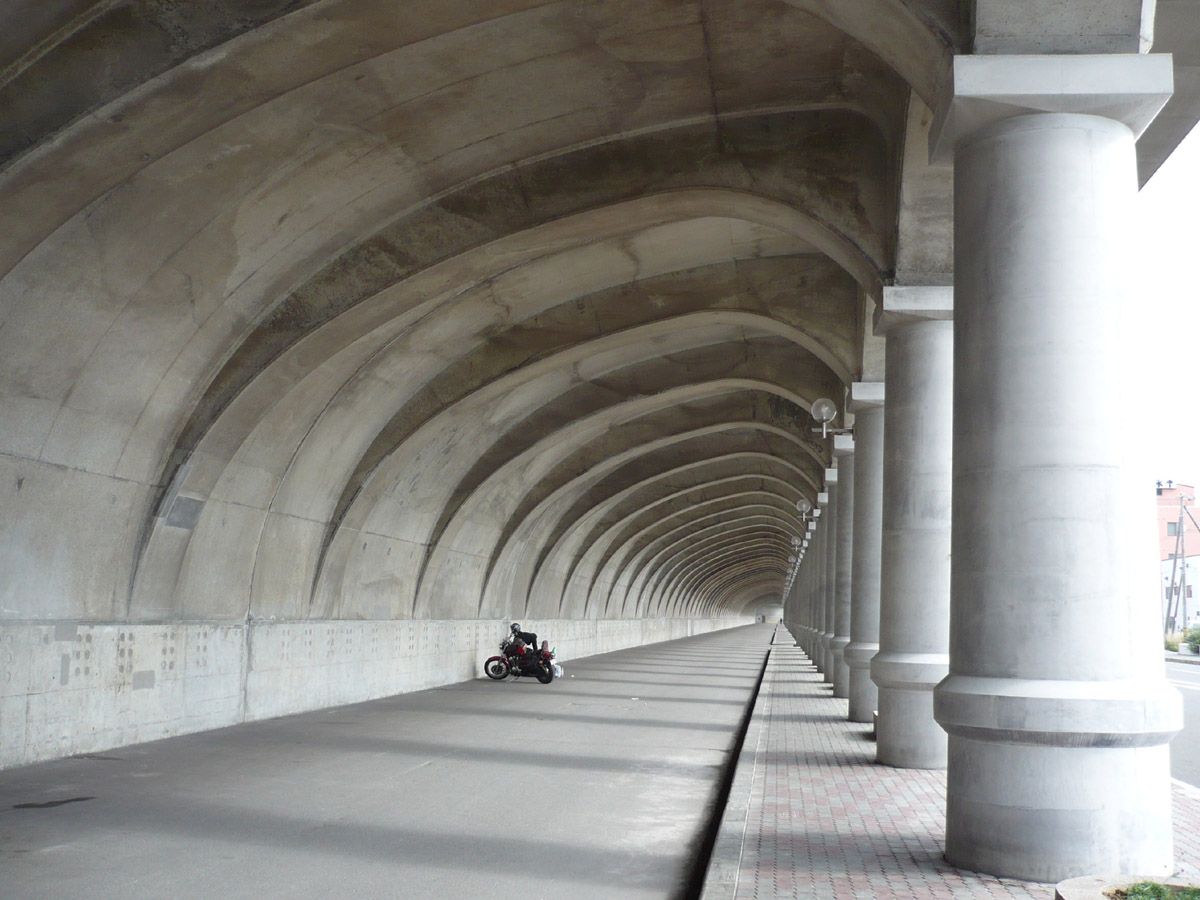 someone riding a motorcycle on a walkway in the tunnel