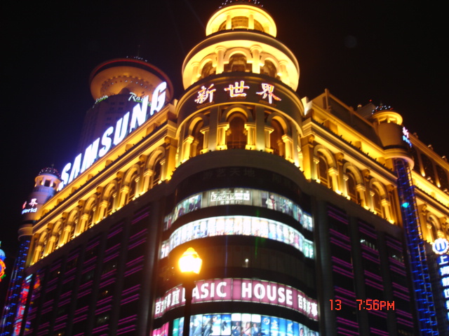 lighted buildings at night with various advertits on top