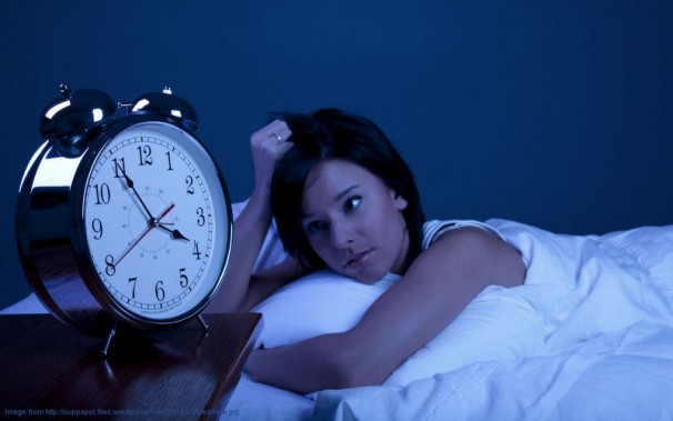 the girl is in bed near an alarm clock