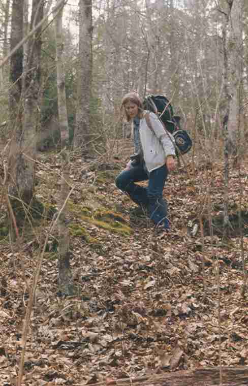 a person walking in the woods holding a backpack