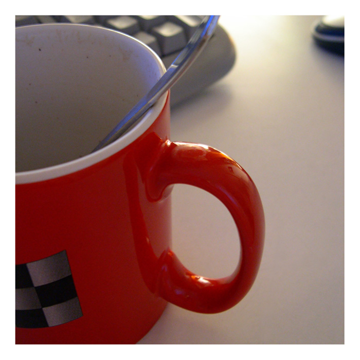 a red mug sits beside a keyboard with a blue spoon