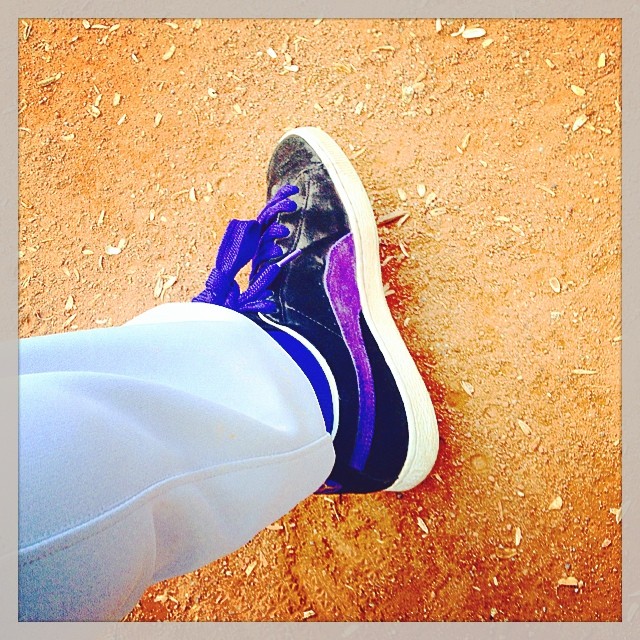 a close - up view of a person's foot wearing white pants and purple shoes