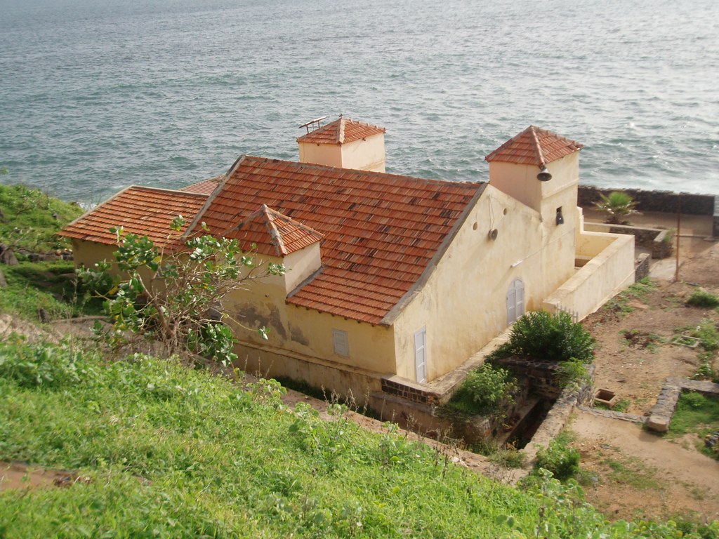 old abandoned house with red roof overlooking a body of water