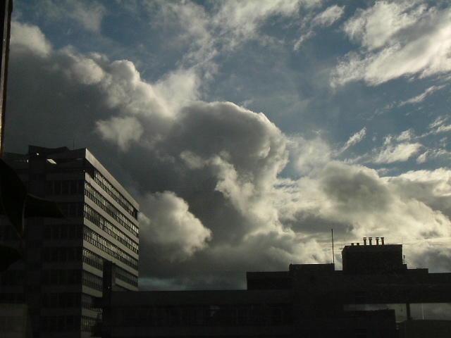 a large cloud hovers over the tops of buildings