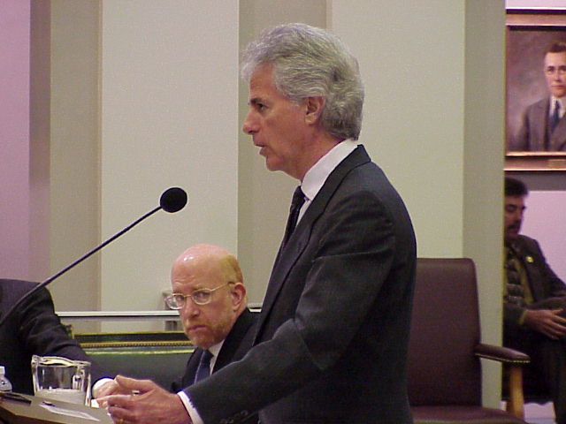 a man with grey hair and in business suit and tie gives a lecture