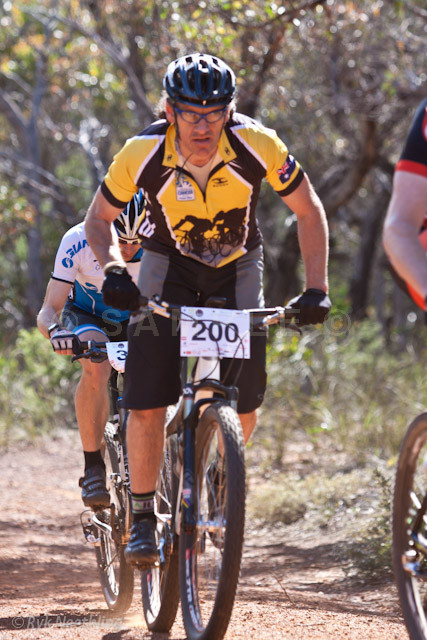 two men are on their bicycles in the dirt