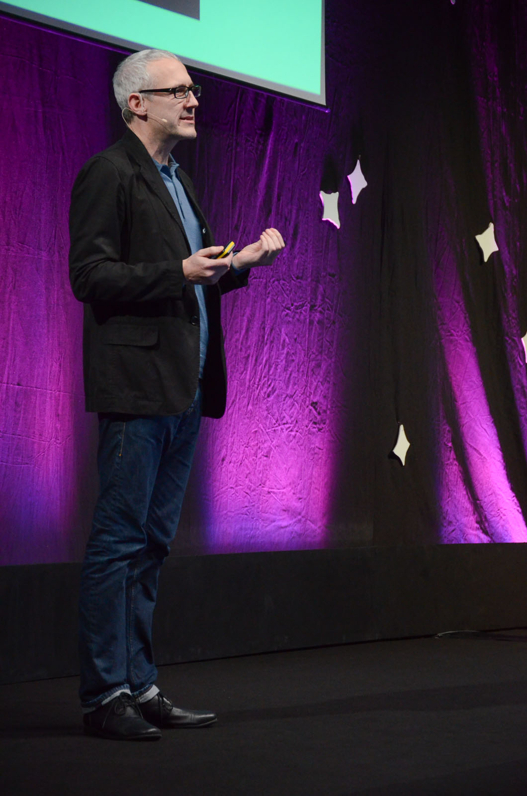 the man is standing in front of a large purple wall and gesturing to someone