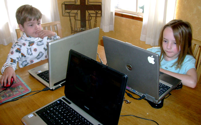 two children are sitting in front of laptops