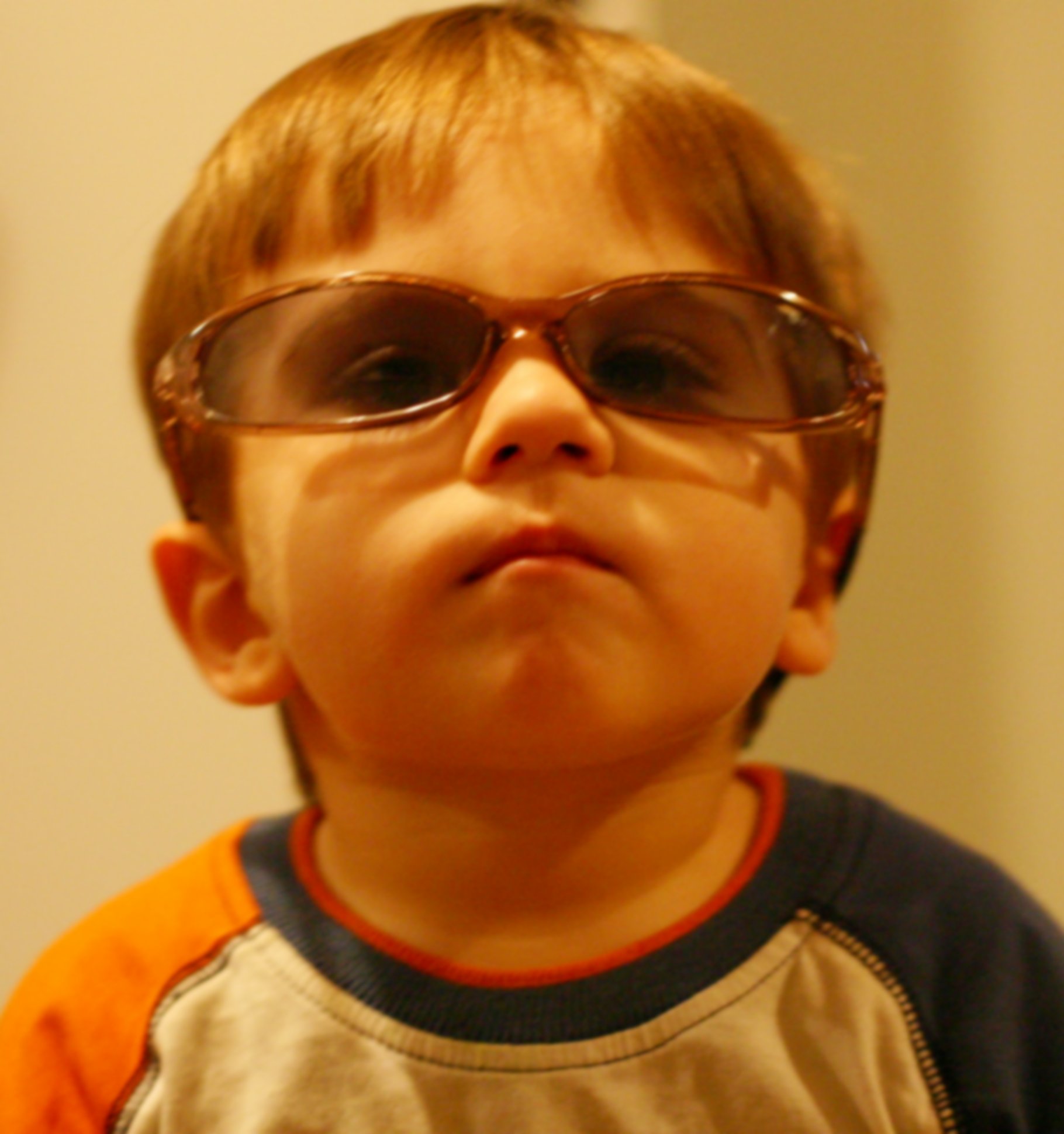 a small child wearing large glasses stands and stares