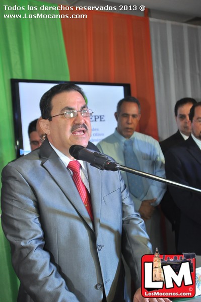 a man speaking into microphone next to a group of men