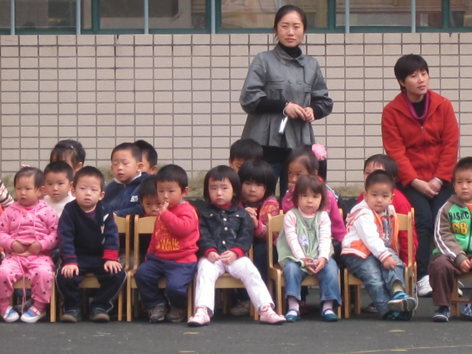 a group of children sit on wooden chairs next to each other