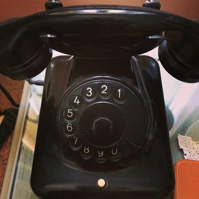 an antique telephone sitting on a table and one has a black dial