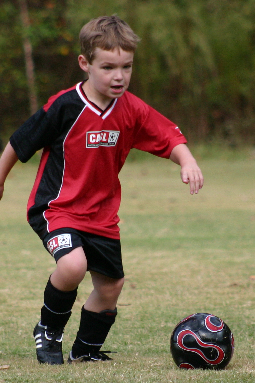 a small boy kicking around a soccer ball