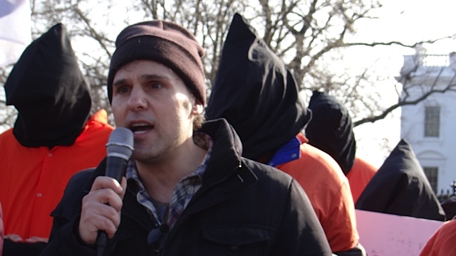man talking into a microphone while wearing a beanie