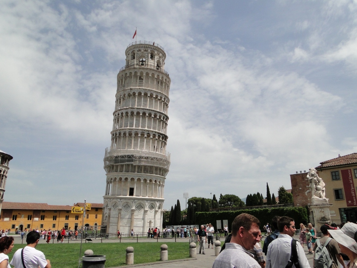 many people standing around the tall tower and buildings
