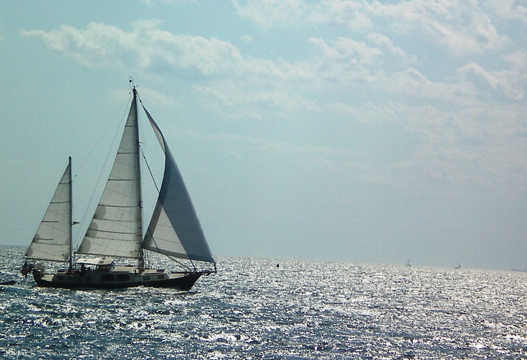 sailboat with white sails on open water