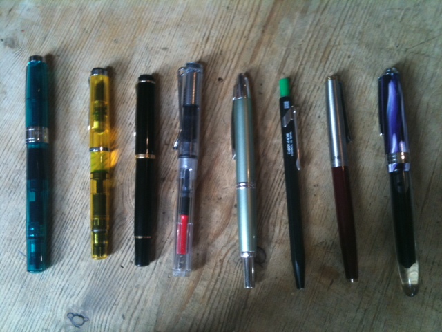 several different pens are laying out on a table
