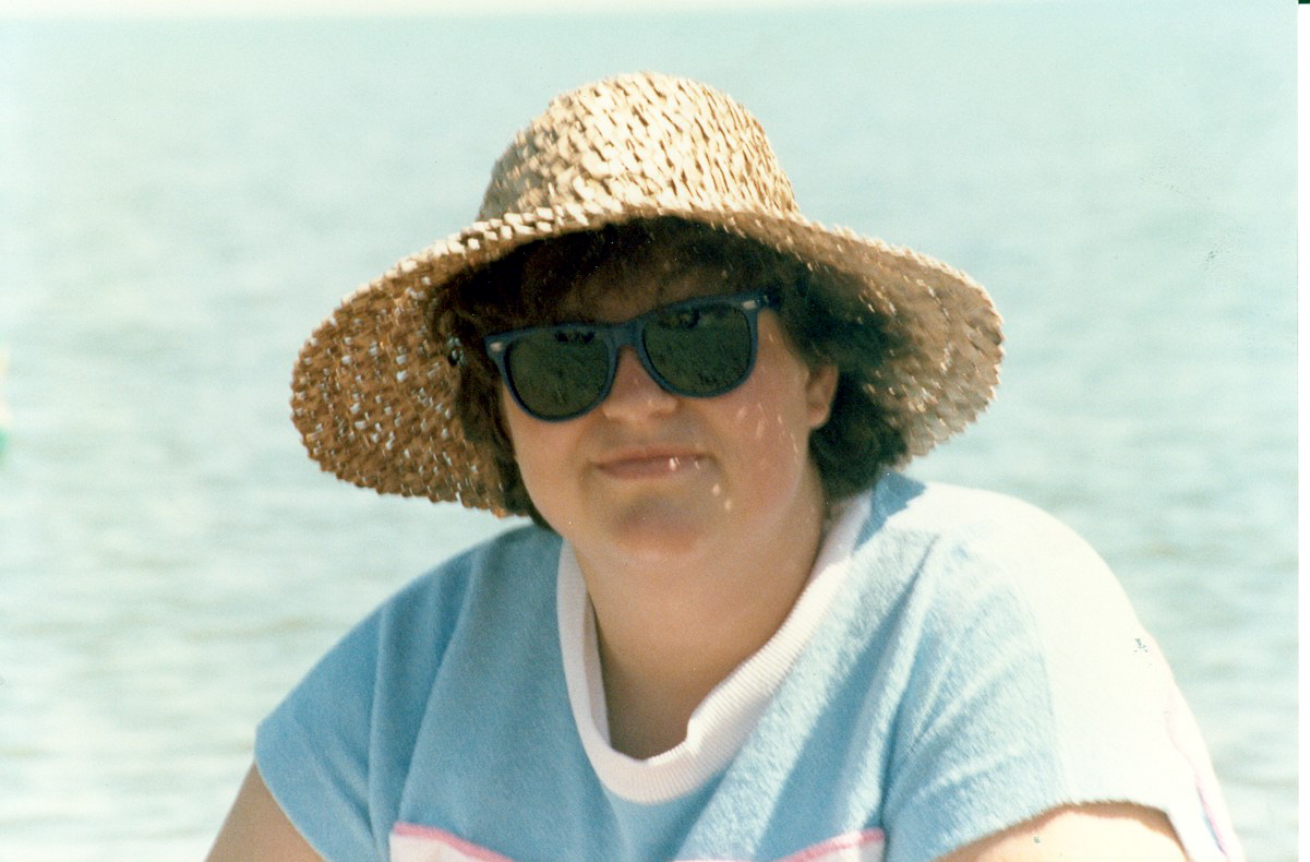 a woman is sitting down wearing a straw hat