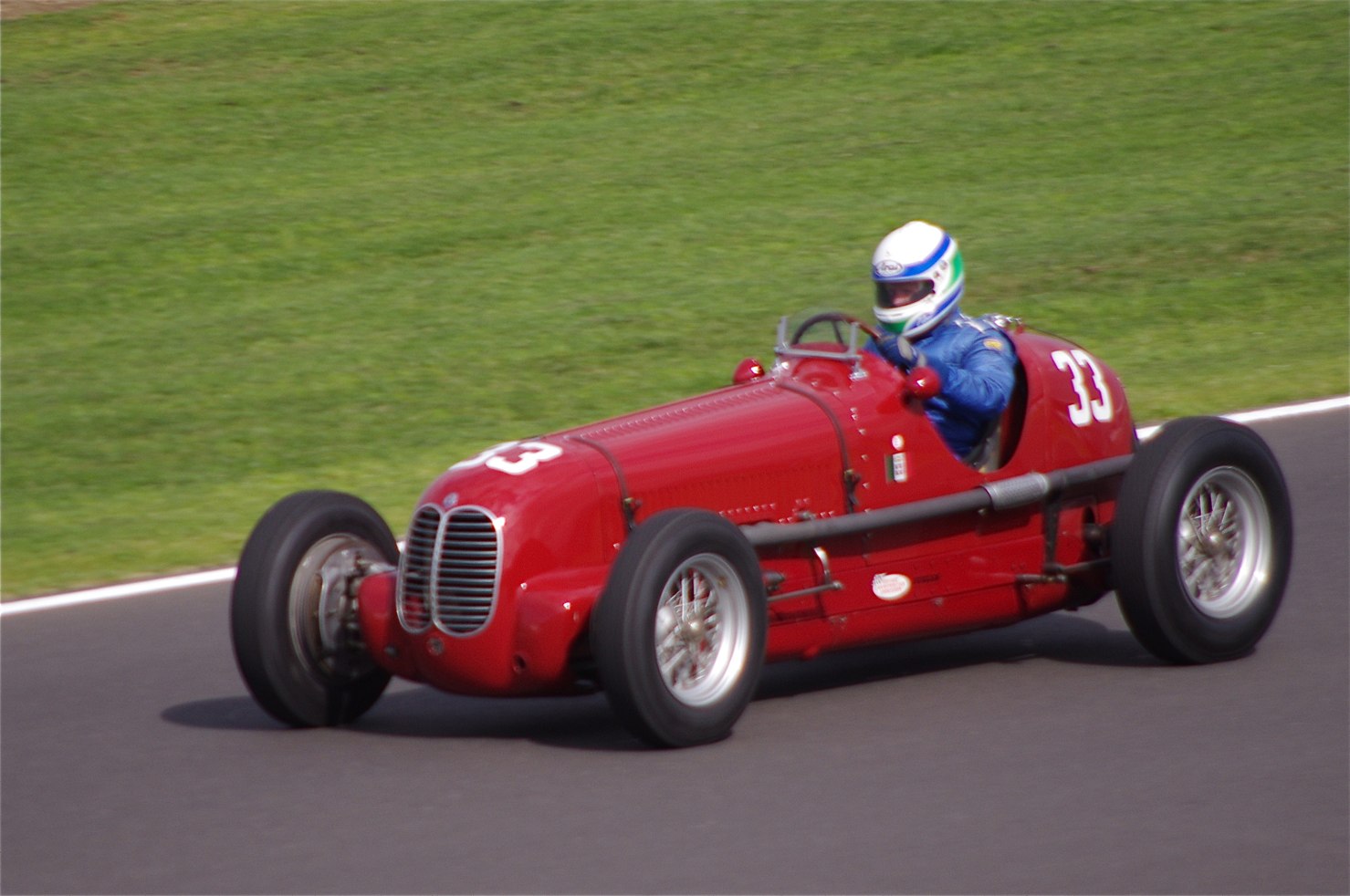 a red race car on the road with a person driving it