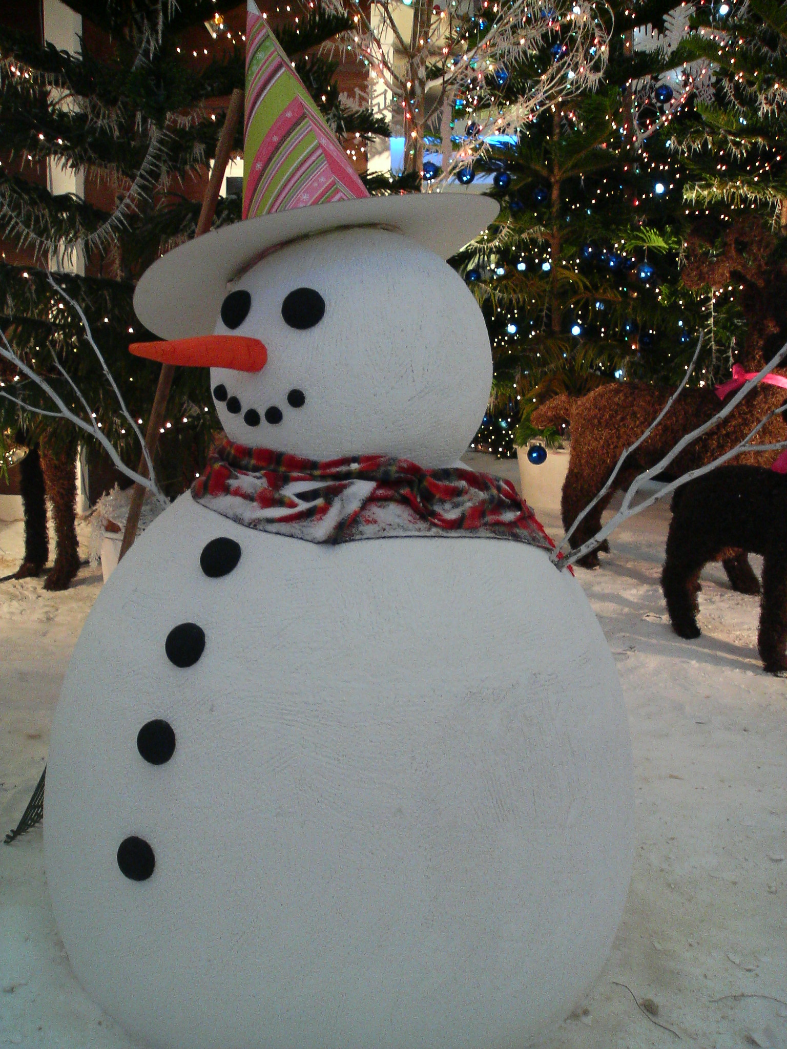 the large snowman has a red and green plaid scarf on it's neck