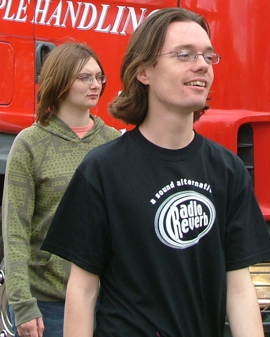 a man and woman are standing in front of a big truck