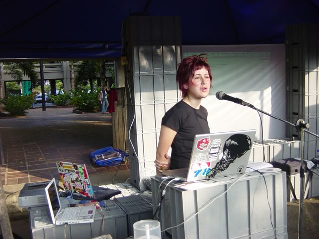 a woman standing behind a microphone and holding a laptop