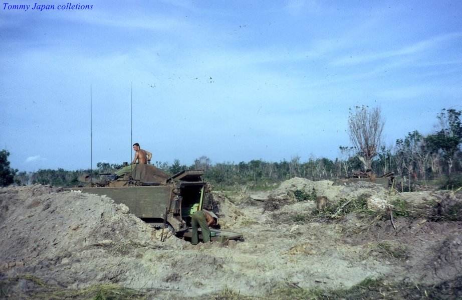 two soldiers in a large open area near a tank
