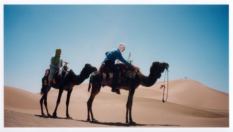people riding on two camels in the desert