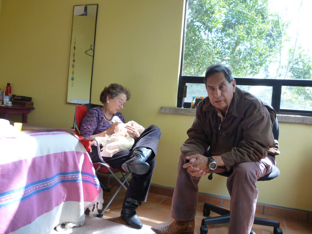 a woman sitting in a chair near a man with his hand on the table