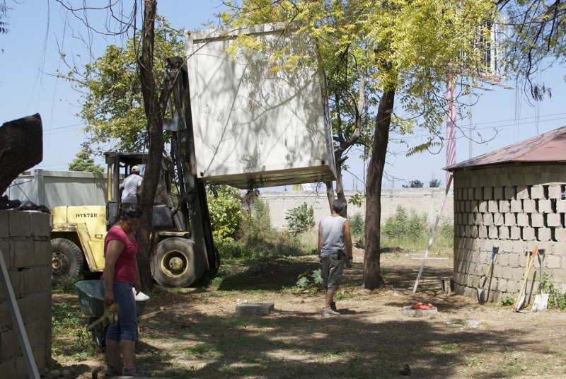 three men move a large trailer from a trailer house to another building