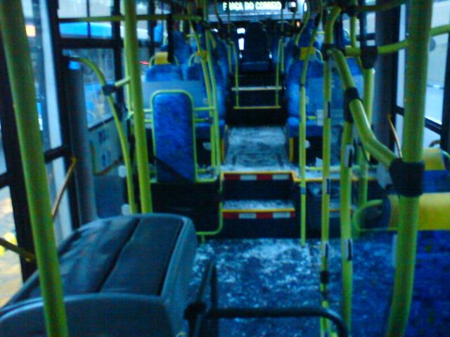 a long bus with blue seat covers and yellow arms