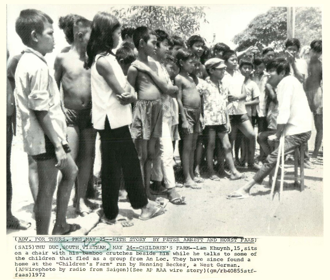 the picture shows a black and white po of a boy standing in front of children in front of an audience